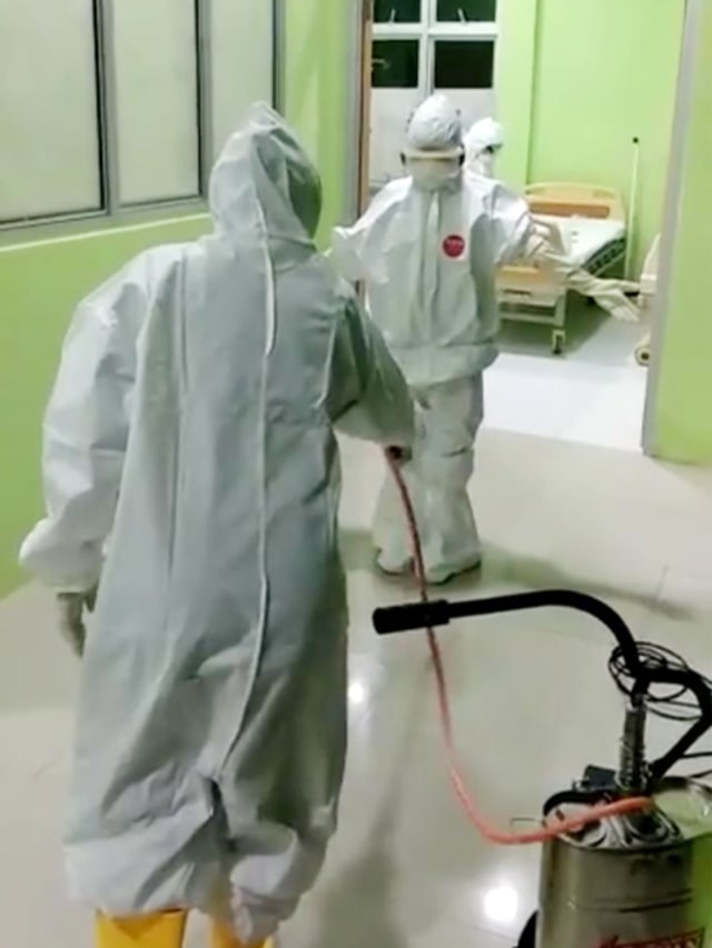 Petugas menyemprotkan cairan disinfektan sebelum diperbolehkan memasuki ruangan isolasi di RSUD Bolmut