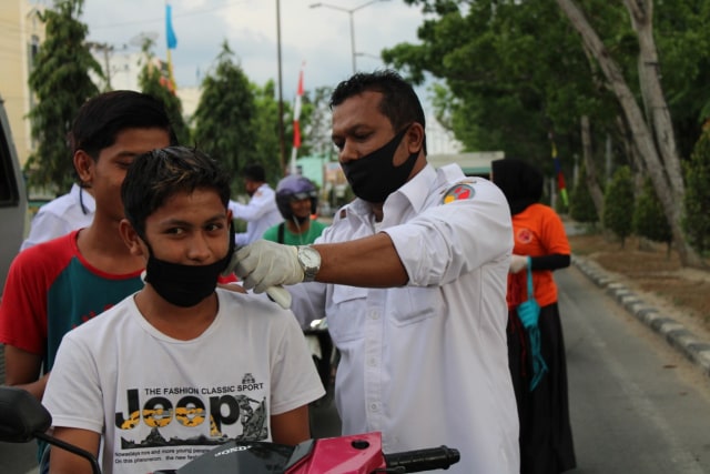 Ketua Panwaslih Aceh Tamiang, Imran ikut membagikan masker kepada warga. Foto-foto: Panwaslih Aceh Tamiang  