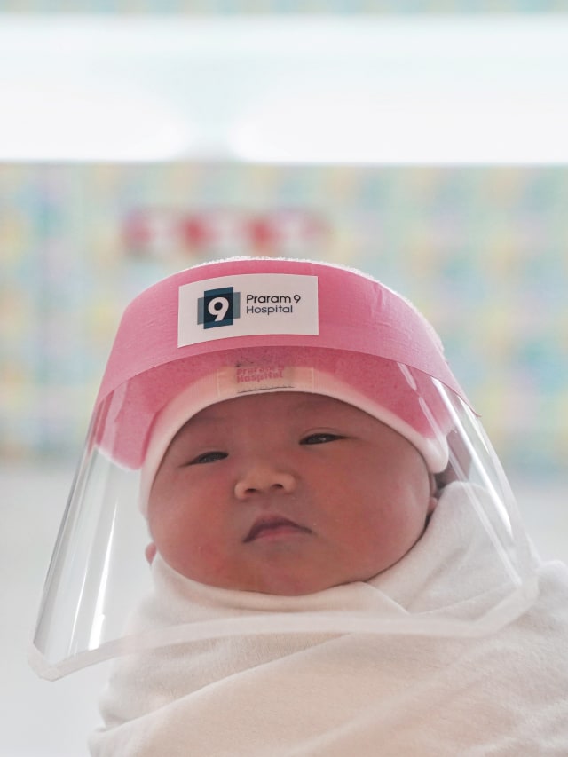 Bayi yang baru lahir memakai pelindung wajah di rumah sakit Praram, Bangkok, Thailand. Foto: REUTERS / Athit Perawongmetha