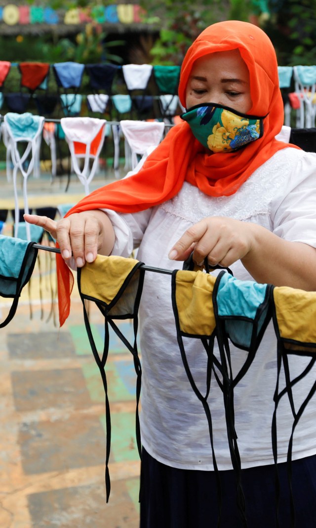Seorang wanita sedang menjemur masker sebelum membagikannya secara gratis di sekitar lingkungan, di tengah penyebaran wabah penyakit virus corona, di Tangerang. Foto: REUTERS/Willy Kurniawan