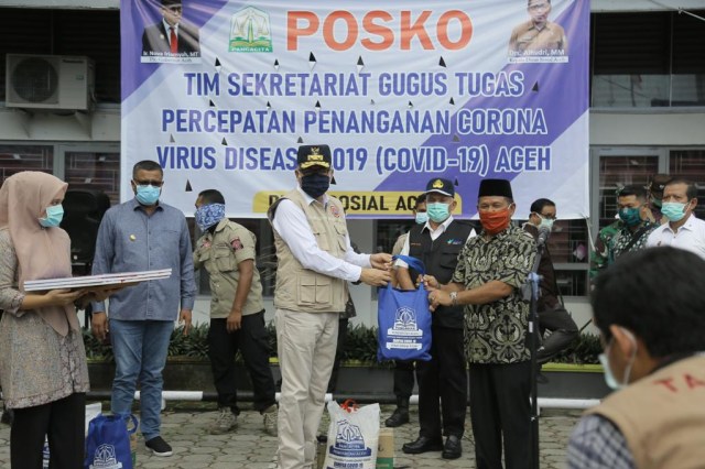 Plt Gubernur Aceh Nova Iriansyah menyerahkan bantuan kebutuhan bahan pokok program social safety net secara simbolis di halaman Kantor Dinsos Aceh untuk keluarga terdampak corona, Kamis (9/4). Foto: Dok. Humas Aceh