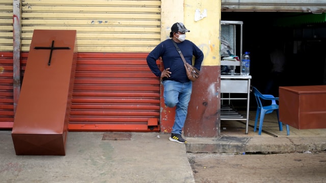 Seorang pria terlihat di sebelah peti mati logam yang dibuat di bengkel logam saat penyakit coronavirus (COVID-19) membanjiri otoritas sanitasi, di Guayaquil. Foto: REUTERS/Vicente Gaibo