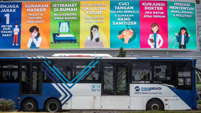Bus TransJakarta melintas di bawah papan imbauan pencegahan penyebaran virus corona. Foto: ANTARA/Aprillio Akbar
