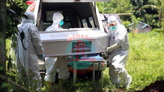 Peti Jenazah diturunkan dari mobil ambulance oleh sukarelawan yang membantu untuk menguburkan jenazah (foto: febry kodongan/manadobacirita)