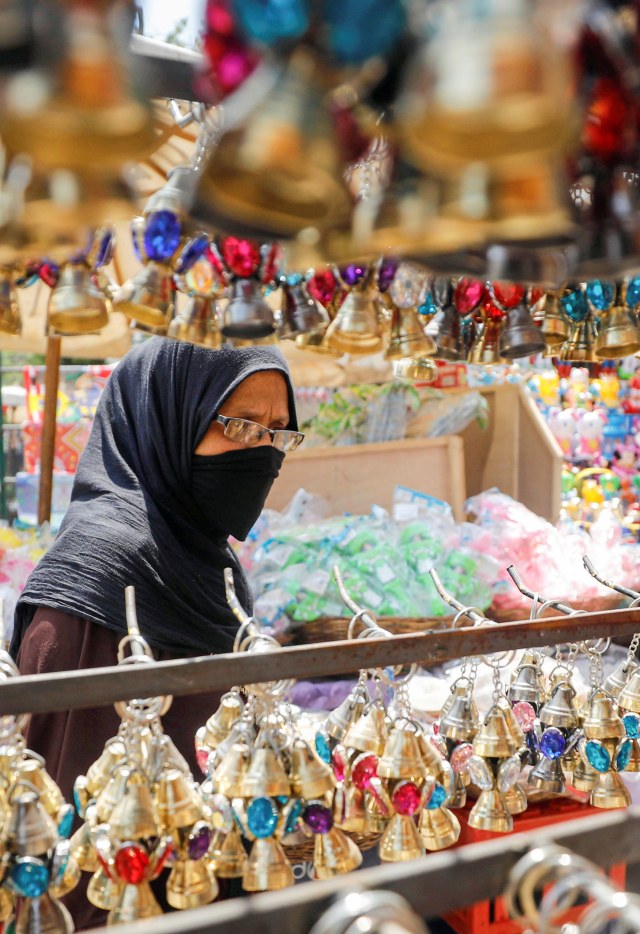 Seorang wanita menggunakan masker membeli lentera 'Fanous' di sebuah kios di Kairo, Mesir. Foto: REUTERS / Mohamed Abd El Ghany