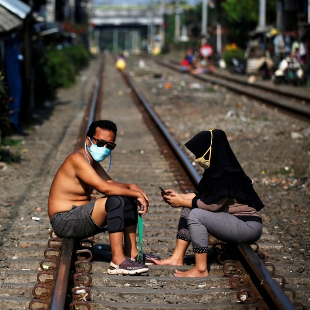 Warga berjemur tengah rel di kawasan Petamburan, Tanah Abang, Jakarta Pusat. Foto: REUTERS/Willy Kurniawan