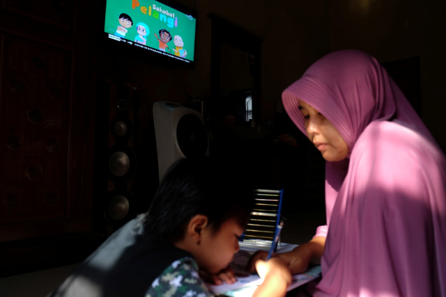 Seorang anak didampingi ibunya belajar dengan melihat tayangan siaran TVRI di rumah mereka, di Deli Serdang, Sumatera Utara, Senin (13/4). Foto: ANTARA FOTO/Irsan Mulyadi