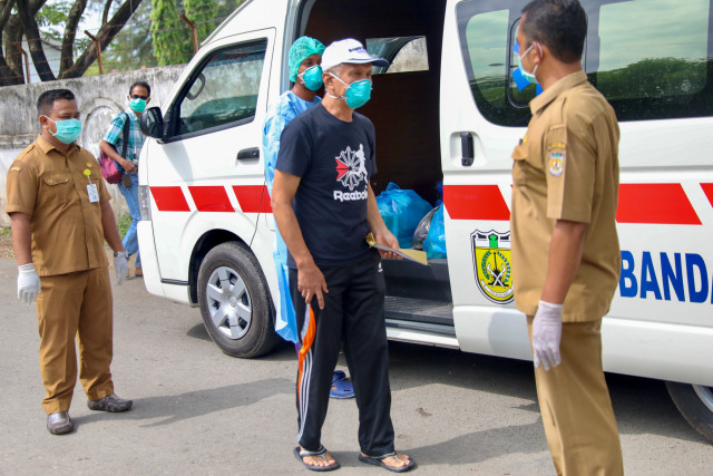 AJ, pasien berusia 60 tahun (bertopi) yang dinyatakan telah sembuh dari COVID-19 siap diantarkan ke rumahnya usai diperbolehkan pulang dari ruang RICU RSUDZA Banda Aceh, Senin (13/4). Foto: Suparta/acehkini