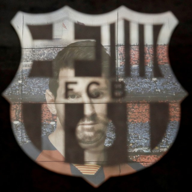 Gambar Lionel Messi terpantul di logo Barcelona. Foto: Reuters/Albert Gea