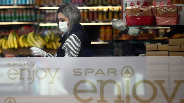 Seorang karyawan supermarket mengenakan masker dan sarung tangan di Wina, Austria. Foto: REUTERS / Lisi Niesner
