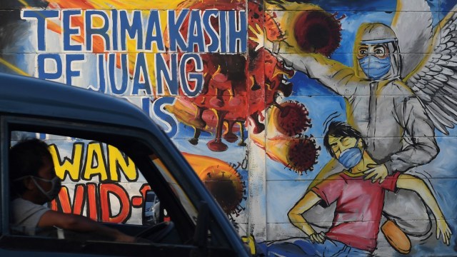 Seorang supir angkot melintasi mural ajakan melawan COVID-19 di Depok, Jawa Barat, Selasa (14/4). Foto: ANTARA FOTO/Wahyu Putro A