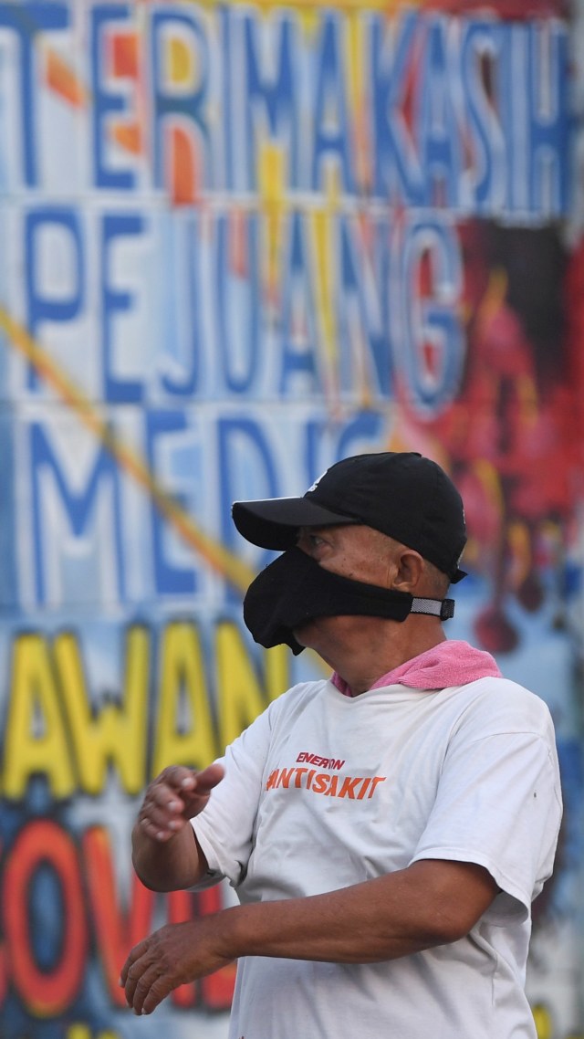 Seorang warga berolah raga dengan latar belakang mural ajakan melawan COVID-19 di Depok, Jawa Barat, Selasa (14/4). Foto: ANTARA FOTO/Wahyu Putro A