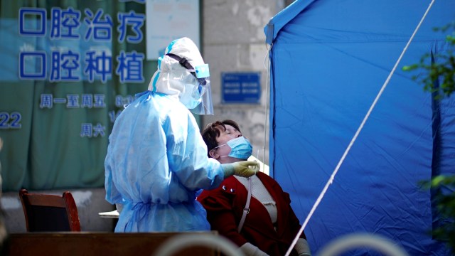 Seorang pekerja medis yang memakai pakaian pelindung melakukan uji asam nukleat kepada seorang warga di Wuhan, Provinsi Hubei, China. Foto: REUTERS/Aly Song