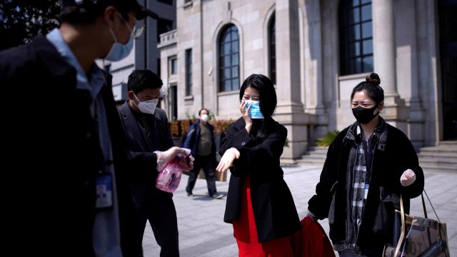 pereSeorang tim dari fotografer menyemprotkan disinfektan kepada pasangan pengantin perempuan saat sesi foto untuk pernikahan di Wuhan, Hubei, China, Minggu (12/4). Foto: REUTERS/Aly Song