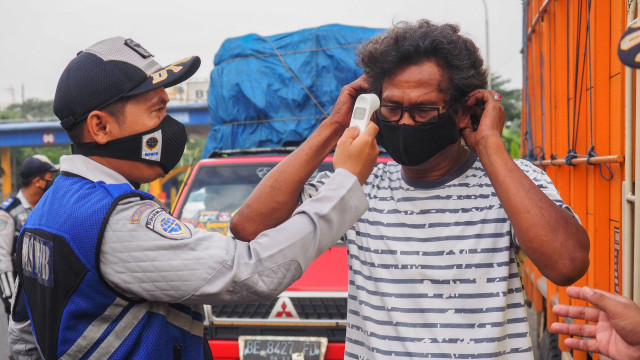 Petugas gabungan Polri dan Dishub memantau suhu tubuh pengendara dan penumpang kendaraan yang memasuki Kota Bekasi. Foto: ANTARA/Paramayuda