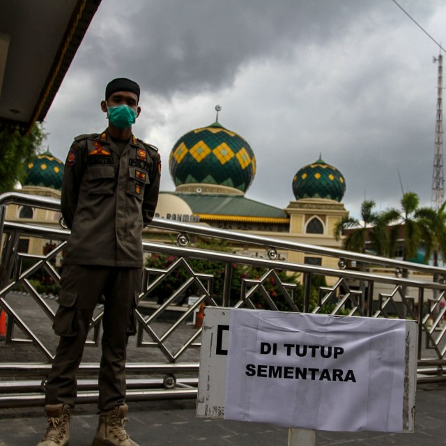 Petugas Satpol PP Kota Pekanbaru berjaga di depan pintu masuk Masjid Agung Ar-Rahman, Pekanbaru, yang ditutup sementara, Jumat (20/3). Foto: ANTARA FOTO/Rony Muharrman