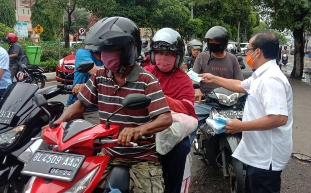 Pejabat Pemprov Aceh membagikan masker ke pengguna jalan di Banda Aceh, Jumat (17/4). Foto: Humas Aceh