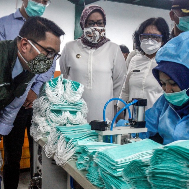 Gubernur Jawa Barat Ridwan Kamil (kiri) didampingi Bupati Bogor Ade Yasin (tengah) melihat produksi pembuatan masker medis. Foto: ANTARA/Yulius Satria Wijaya