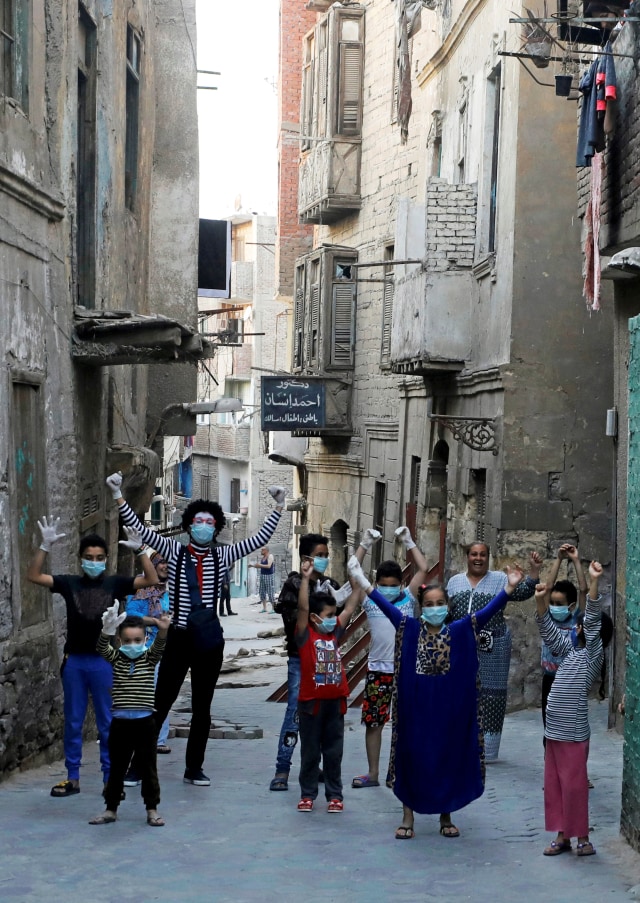 Seniman pantomim Ahmad Naser bersama anak-anak usai memberikan hiburan sebagai bentuk pencegahan corona di distrik Darb Al-Ban, Islamic Cairo, Mesir. Foto: REUTERS/Mohamed Abd El Ghany