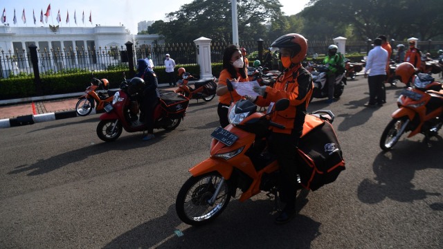 Pegawai PT POS Indonesia (Persero) berkoordinasi sebelum pelepasan distribusi bantuan sosial sembako di depan Istana Merdeka, Jakarta, Senin (20/4). Foto: ANTARA FOTO/Sigid Kurniawan