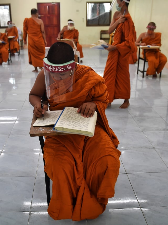 Sejumlah biksu muda menggunakan masker dan pelindung wajah (Face Shield) mengikuti studi agama di kuil Buddha Wat Molilokkayaram, Bangkok, Thailand. Foto: AFP/Lillian SUWANRUMPHA