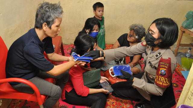 Personel Dit Samapta Polda Sumut Bripda Tika Sinaga memberikan bantuan sembako dan masker kepada warga kurang mampu di Medan, Sumatera Utara, Selasa (21/4). Foto: ANTARA FOTO/Septianda Perdana