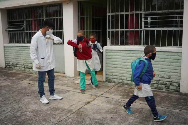 Guru Sergio Ferrao memberikan salam siku kepada para muridnya di  Escuela 30, San Jose, Uruguay, Kamis (23/4). Foto:  REUTERS/Mariana Greif