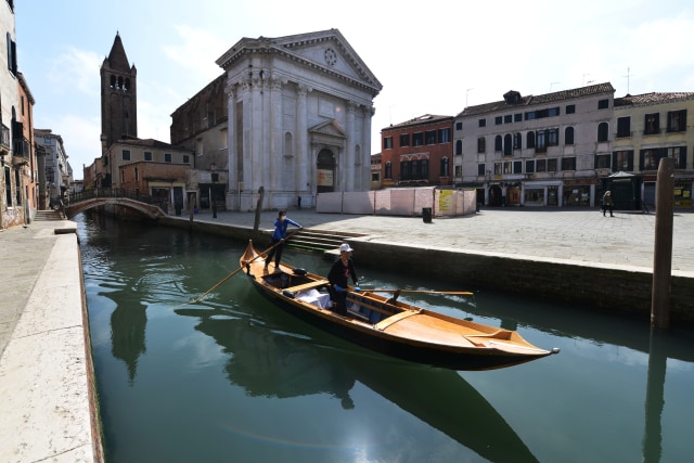 Anggota dari Row Venice membawa makanan menggunakan gondola yang melintasi kanal Venesia, Italia.  Foto: AFP/ANDREA PATTARO