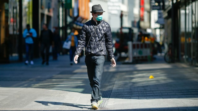 Seorang pria menggunakan masker berjalan di Cologne, Jerman. Foto: REUTERS / Thilo Schmuelgen