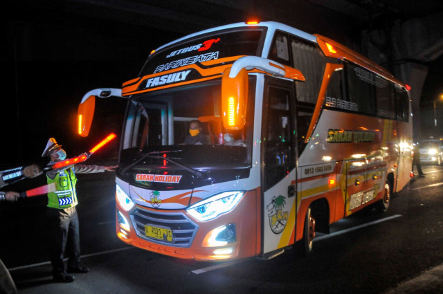 Polisi menghalau mobil bus yang membawa pemudik di tol Jakarta-Cikampek untuk keluar ke Gerbang tol Cikarang Barat, Kabupaten Bekasi. Foto: ANTARA FOTO/Fakhri Hermansyah