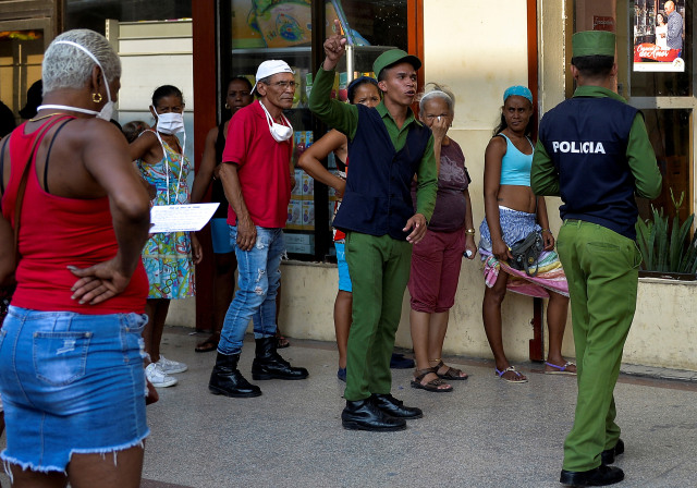 Polisi membantu mengatur orang-orang yang mengantri untuk membeli makanan di tengah wabah virus corona di Havana, Kuba. Foto: Yamil Lage / AFP