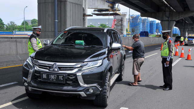 Sejumlah polisi menghentikan pengemudi kendaraan yang tidak menerapkan jarak sosial di tol Jakarta-Cikampek, Cikarang, Kabupaten Bekasi, Jawa Barat. Foto: ANTARA FOTO/ Fakhri Hermansyah