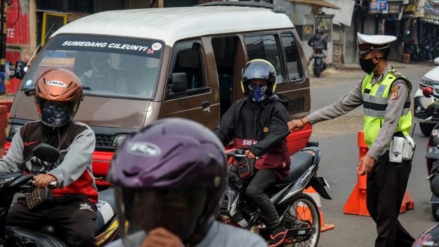 Petugas memberhentikan kendaraan bermotor di titik penyekatan larangan mudik di Jatinangor, perbatasan Kabupaten Bandung dan Kabupaten Sumedang, Jawa Barat. Foto:  ANTARA FOTO/Raisan Al Farisi