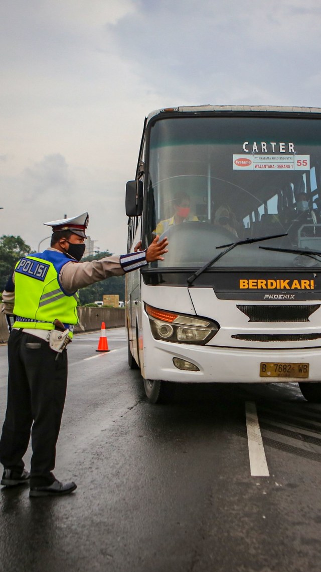 Petugas kepolisian mengarahkan bus ke pintu keluar Tol Bitung, Kabupaten Tangerang, Banten. Foto: ANTARA FOTO/Fauzan