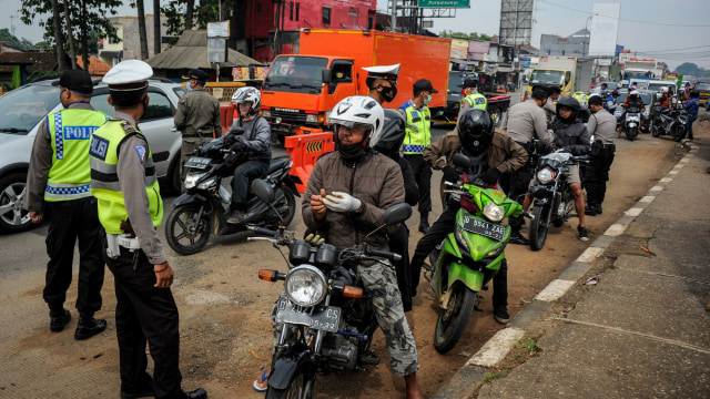 Petugas memberhentikan kendaraan bermotor di titik penyekatan larangan mudik di Jatinangor, perbatasan Kabupaten Bandung dan Kabupaten Sumedang, Jawa Barat. Foto:  ANTARA FOTO/Raisan Al Farisi