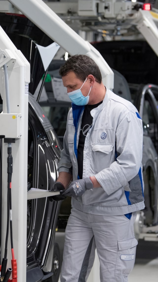 Heiko Gruner mengenakan masker saat bekerja di lini produksi untuk model Volkswagen ID.3 listrik di Zwickau, Jerman. Foto: Hendrik Schmidt/Pool via REUTERS