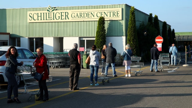 Pengunjung mengantre untuk memasuki Schilliger Garden Centre pada hari pertama pelonggaran lockdown di Gland, Swiss, Senin (27/4). Foto: REUTERS/Denis Balibouse