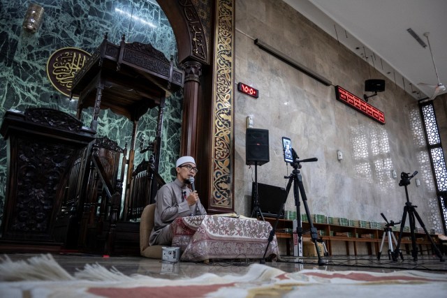Imam Ustaz H Deden M Ramadhan menyiarkan acara tadarus Al-Quran secara daring di Masjid Agung Sunda Kelapa, Jakarta, Senin (27/4). Foto: ANTARA FOTO/Dhemas Reviyanto