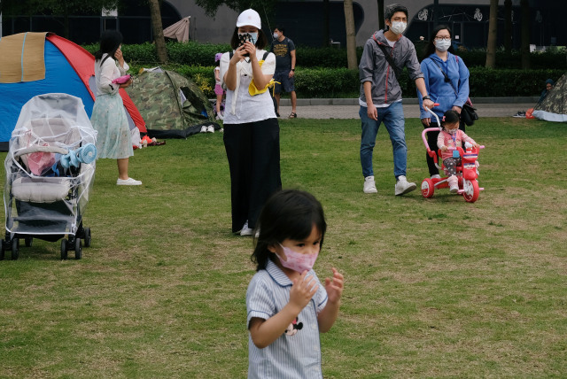 Warga tetap menggunakan masker saat bermain di taman untuk menghindari penyebaran penyakit corona (COVID-19). Foto: REUTERS / Tyrone Siu