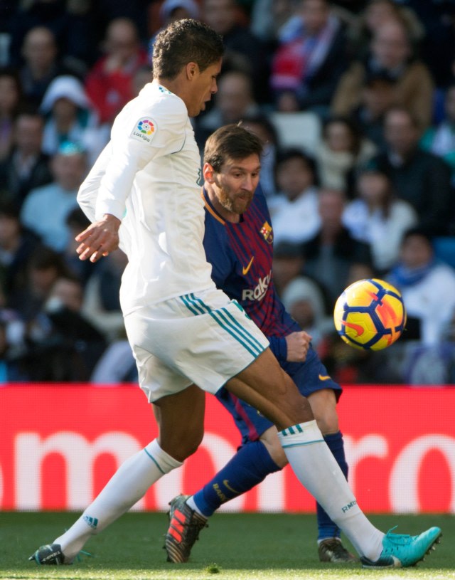 Raphael Varane berupaya menghalangi bola kiriman Lionel Messi. Foto: AFP/Curto de La Torre