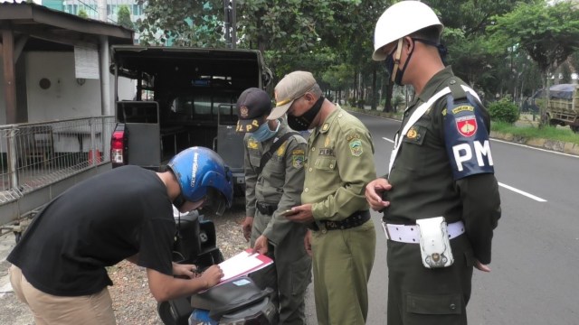 Sejumlah petugas kepolisian mengecek identitas pengendara motor yang melintas di Check point di Kabupaten Banyumas.  Foto: Dok. Pemkab Banyumas
