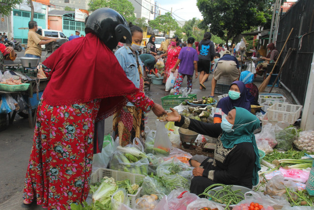 Pedagang melayani pembeli di pasar tumpah di kawasan Tembok Dukuh, Surabaya, Jawa Timur, Rabu (29/4/2020). Foto: ANTARA FOTO/Didik Suhartono