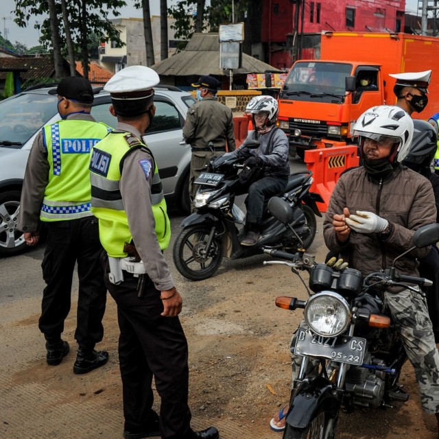 Petugas memberhentikan kendaraan bermotor di titik penyekatan larangan mudik di Jatinangor, perbatasan Kabupaten Bandung dan Kabupaten Sumedang, Jawa Barat. Foto: ANTARA FOTO/Raisan Al Farisi