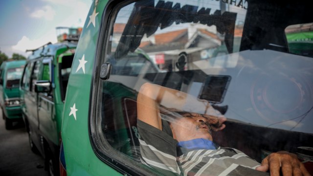 Seorang sopir angkot tertidur di dalam kendaraannya di Terminal Cicaheum, Bandung, Jawa Barat, Rabu (29/4/2020). Foto: ANTARA FOTO/Raisan Al Farisi