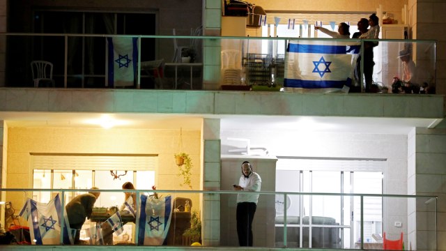 Warga Israel merayakan di balkon rumah mereka pada malam pembukaan Hari Kemerdekaan Israel yang ke-72 di Ashkelon, Israel, Selasa (28/4). Foto: REUTERS/Amir Cohen