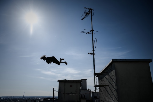 Pelari bebas Prancis Simon melakukan aksi lompatan di atas atap di Paris, Prancis. Foto: AFP/Philippe LOPEZ