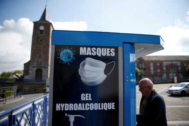 Seorang warga menggunakan vending machine yang menjual masker, hidroalkohol, dan sarung tangan yang dipasang di alun-alun di Jeumont, Prancis. Foto: REUTERS/Pascal Rossignol