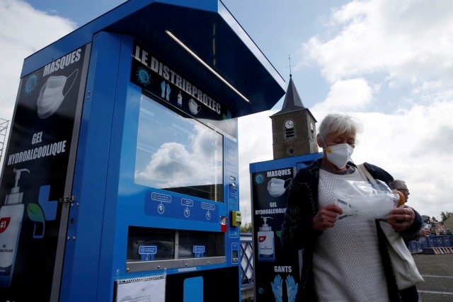 Warga membeli masker di vending machine yang dipasang di alun-alun di Jeumont, Prancis. Foto: REUTERS/Pascal Rossignol