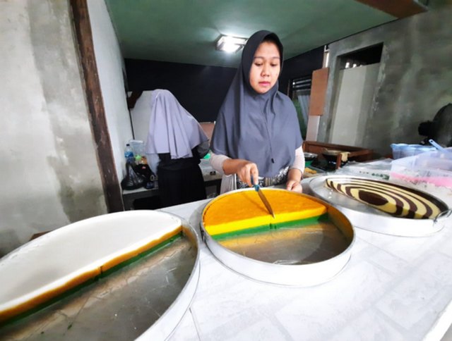 Khairunnisa sedang memotong kue talam yang menjadi menu favorit para pelanggan setianya. | Photo by Karja/Titiantoro