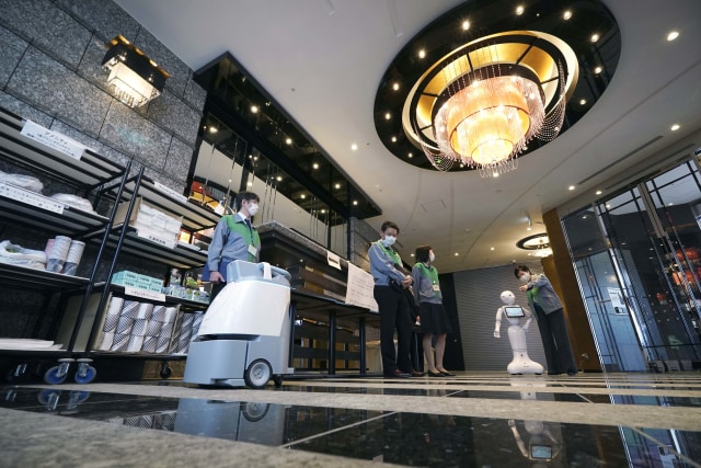 Sebuah robot humanoid Pepper yang mengenakan masker wajah menyambut Gubernur Tokyo Yuriko Koike di lobi hotel untuk pasien coronavirus COVID-19. Foto: AP / Eugene Hoshiko